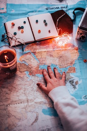 Hand on world map with travel items