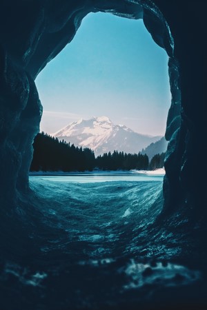 View from an ice cave to a snowy mountain landscape