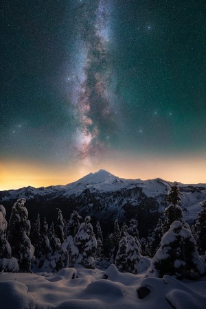 Milky Way over snow-covered mountains and trees