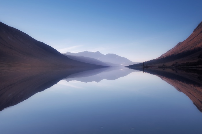 Mountains reflected in a calm loch at sunrise