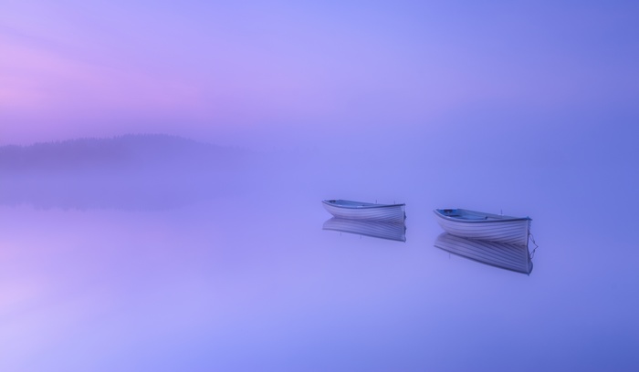 Two rowing boats on a misty lake at sunrise