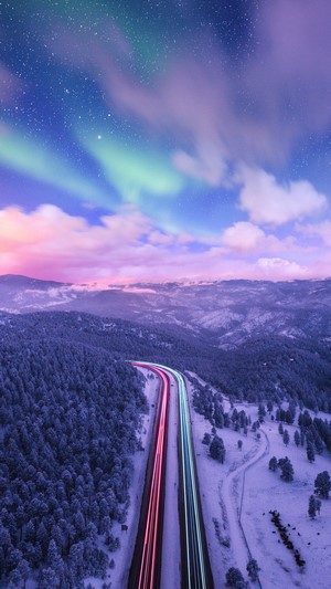 Aurora Borealis over a snowy mountain highway