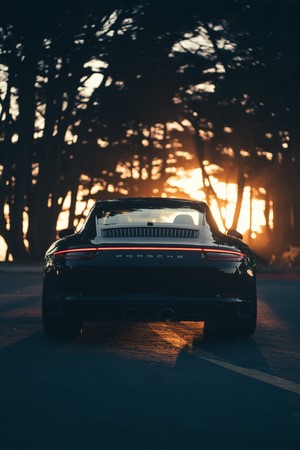 Rear view of a black Porsche 911 at sunset
