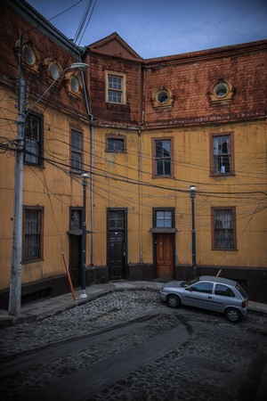 Silver car parked on a cobblestone street in front of a yellow building