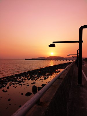Sunset over the sea with a pier and streetlights