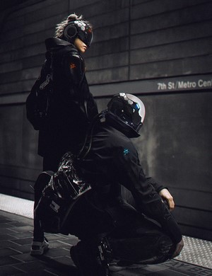 Two figures in futuristic attire at a metro station