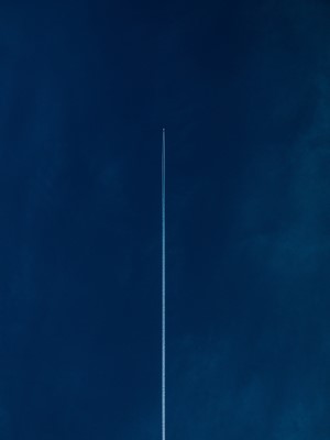 Airplane leaving contrails in a dark blue sky