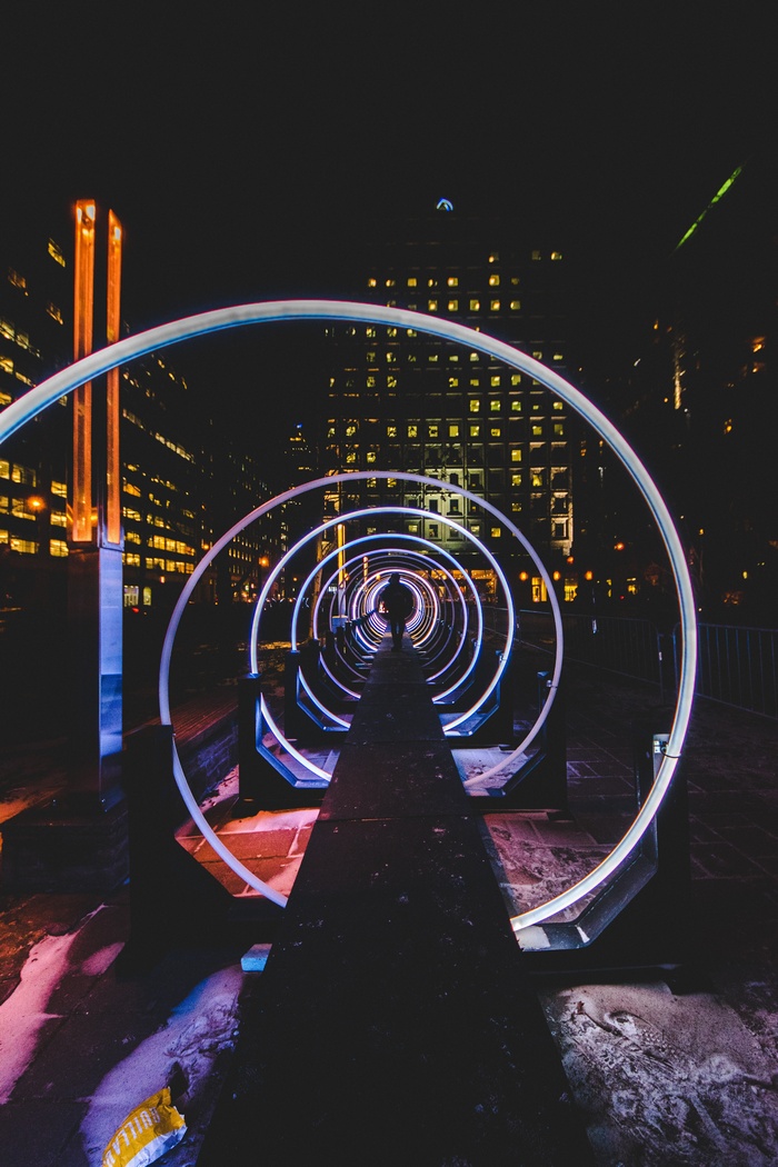 Man walking through a neon spiral tunnel at night