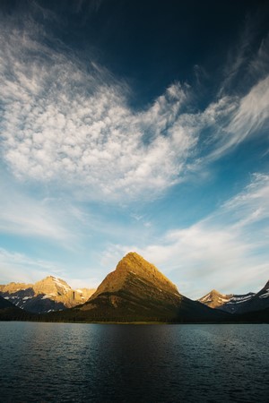 Mountain peak reflected in a lake under a cloudy sky