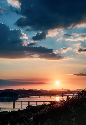 Sunset over a river with bridges and hills