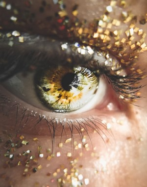 Close-up of a green eye with gold glitter makeup