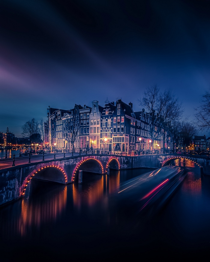 Amsterdam canal at night with illuminated bridge and buildings