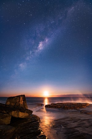 Milky Way over the ocean at sunset with rocks