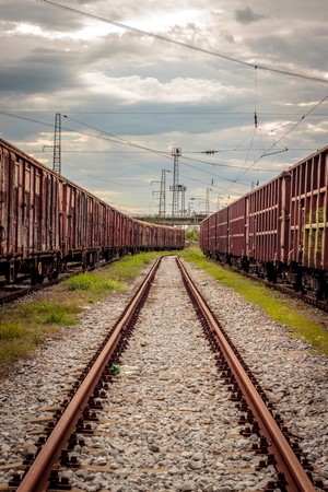 Freight trains on railway tracks under cloudy sky