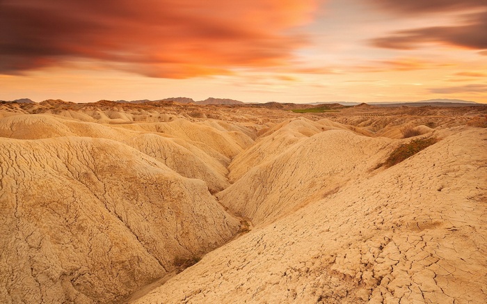 Desert badlands at sunset with dramatic clouds