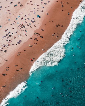 Aerial view of a crowded beach with turquoise ocean waves