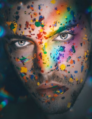 Man with rainbow paint splatters on face