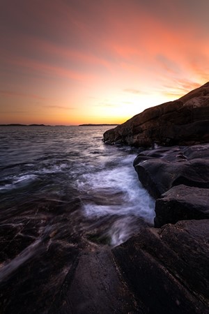 Ocean waves crashing on rocks at sunset