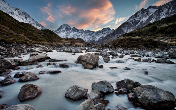River flowing through rocky valley with snow-capped mountains