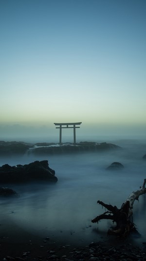 Torii gate in the sea with mist and rocks