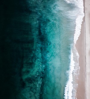 Aerial view of turquoise ocean waves crashing on a sandy beach
