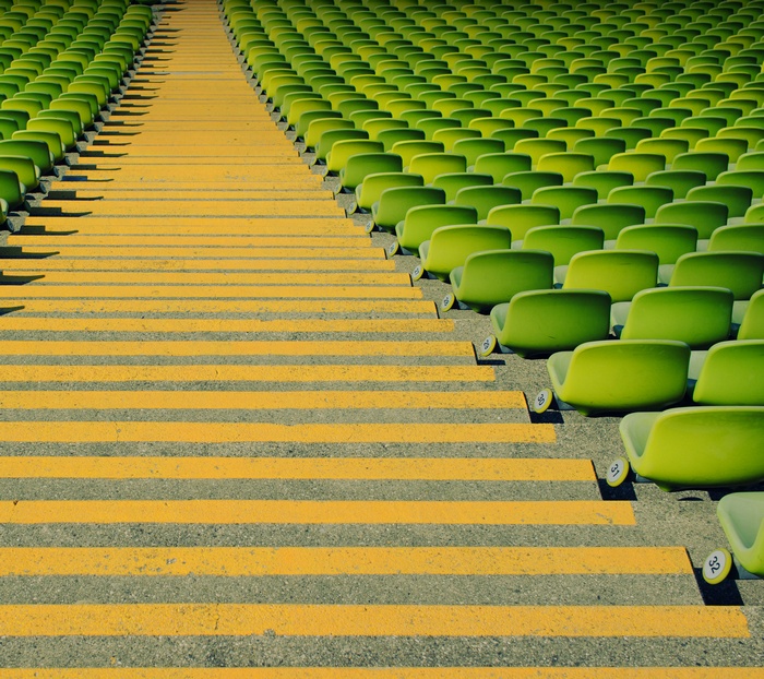 Rows of green stadium seats with yellow striped steps