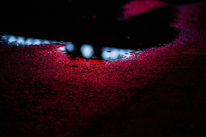 Red liquid and reflections on a dark surface