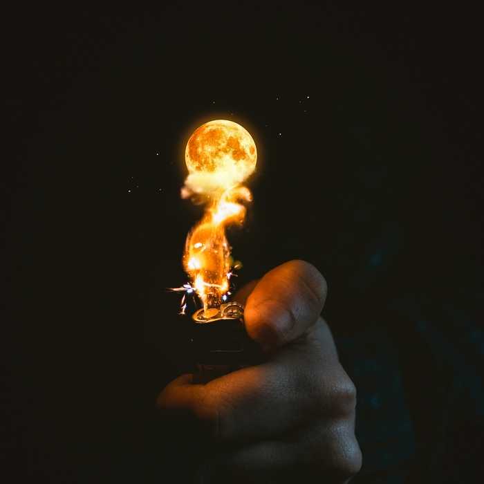 Hand holding a lighter with moon and fire
