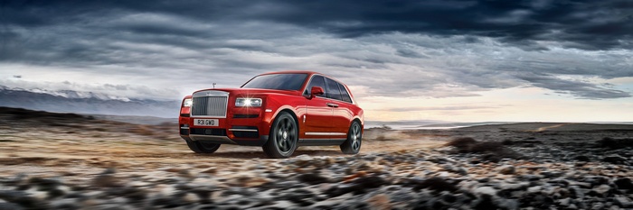 Red Rolls-Royce Cullinan driving on a rocky terrain