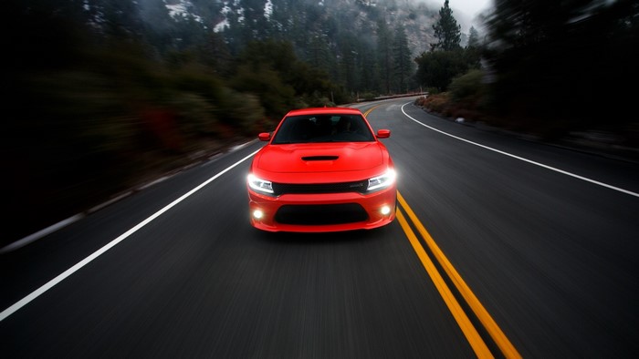 Red Dodge Charger driving on a mountain road