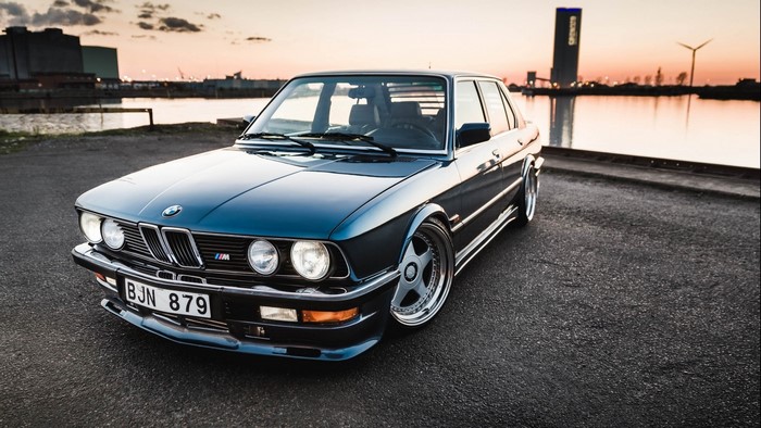 BMW E28 car by the water at sunset