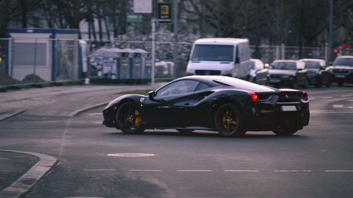 Black Ferrari 488 Italia driving on a city street