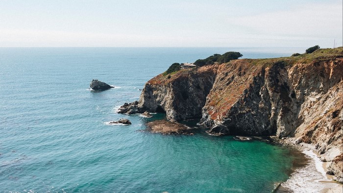 Rocky coastline with turquoise water and a house on the cliff