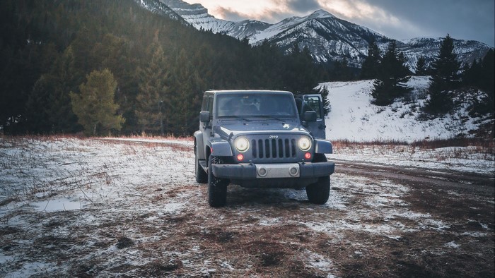 Blue Jeep parked in snowy mountain landscape