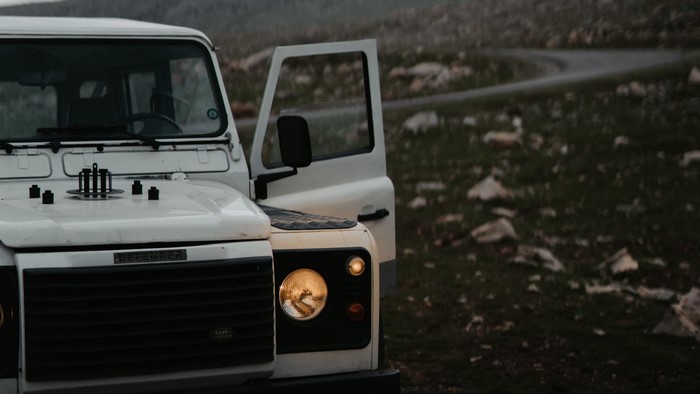 White Land Rover Defender parked on a rocky hill