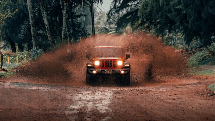 Jeep Wrangler driving through a muddy puddle