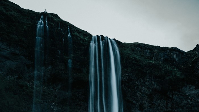 Waterfall cascading down a dark, mossy cliff face