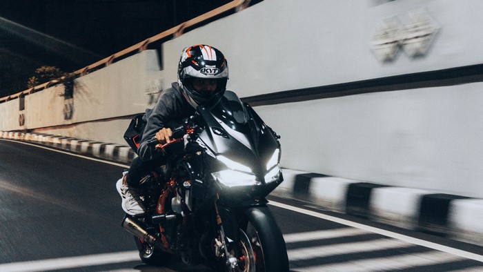 Motorcyclist wearing a helmet riding a sportbike at night