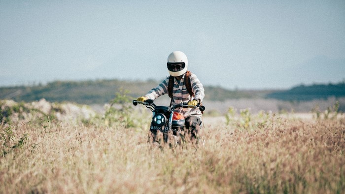 Motorcyclist wearing a helmet riding a motorcycle in a field