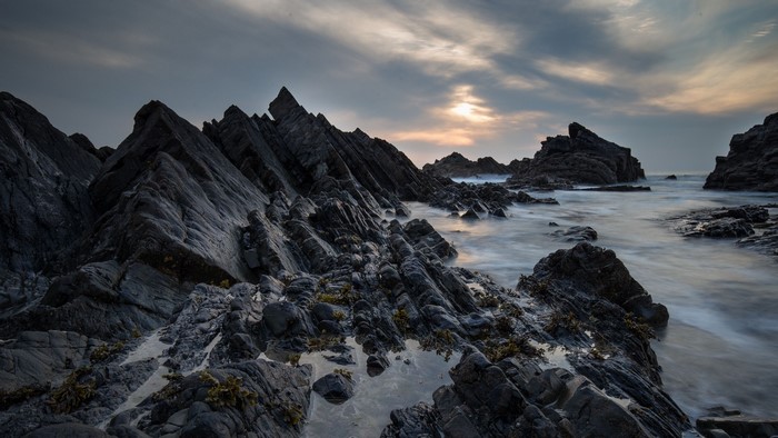 Jagged dark rocks on a rocky coast with ocean waves