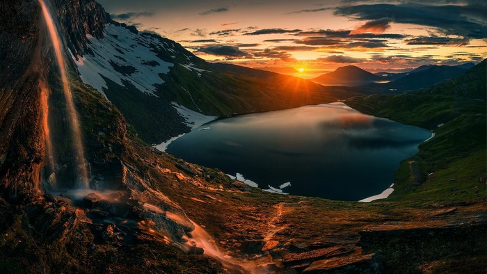 Sunset over a mountain lake with a waterfall