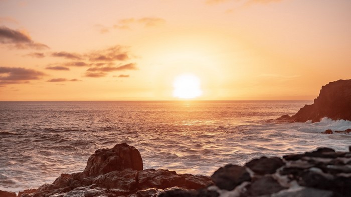 Sunset over the ocean with rocky shore