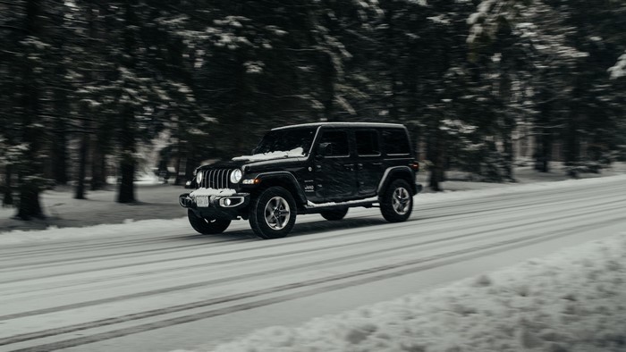 Black Jeep Wrangler driving on a snowy road