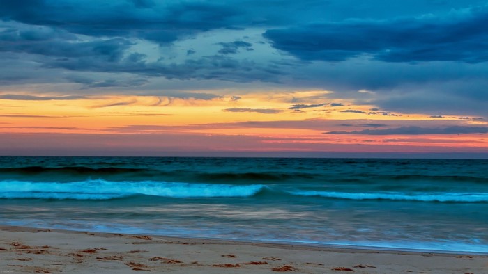 Beach at sunset with colorful sky and ocean waves