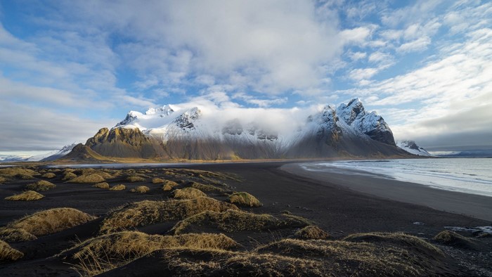 Snow-capped mountains on a black sand beach