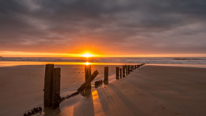 Sunset over a beach with wooden posts
