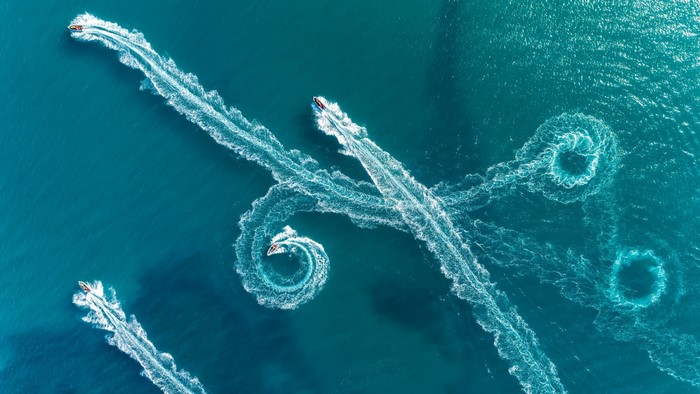 Jet skis creating swirling water trails from above
