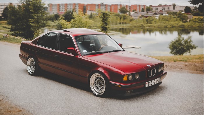 Red BMW E34 Sedan on Road by Lake