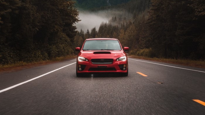Red Subaru WRX STI driving on a foggy mountain road