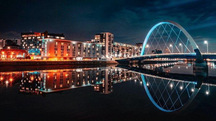 Night cityscape with illuminated bridge and buildings reflected in water
